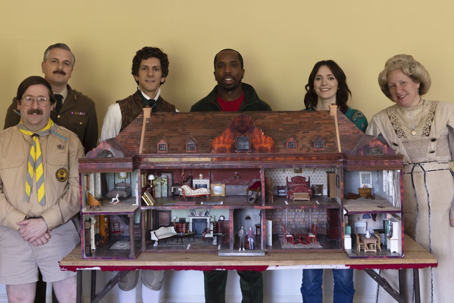 The cast of Ghosts with the dolls house